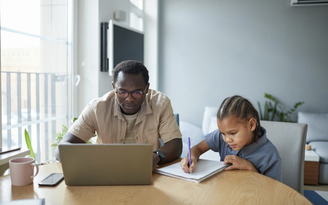 A father working from home, with his kid at the same desk